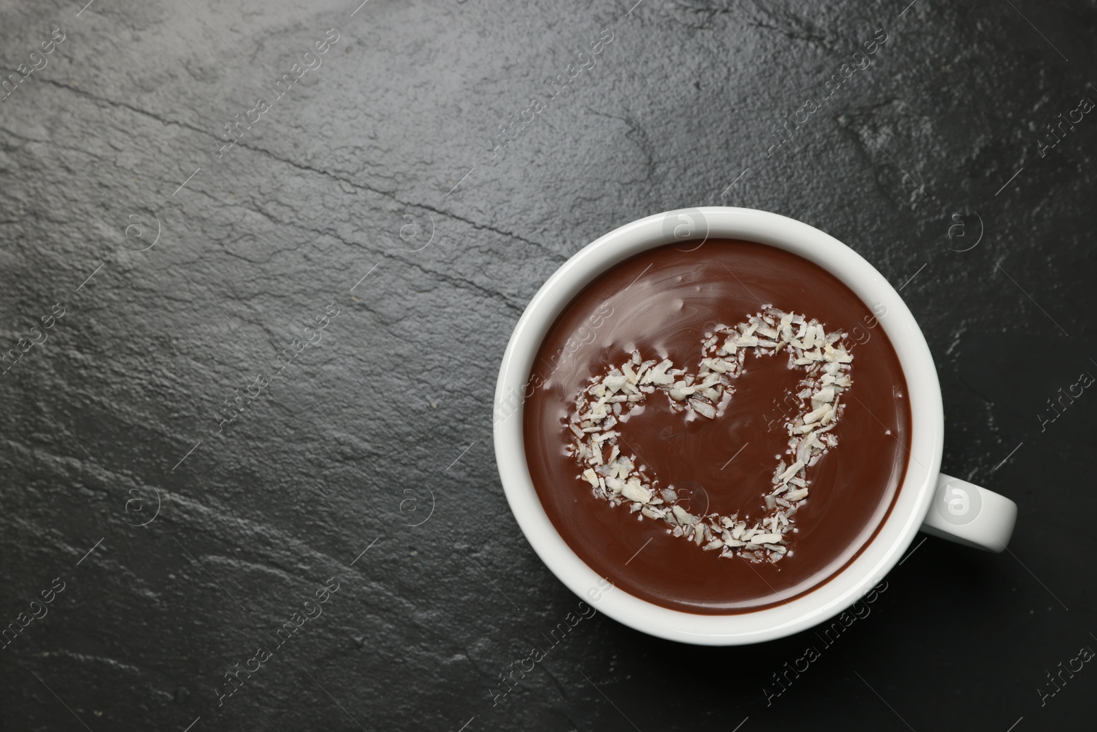 Photo of Cup of hot chocolate with heart shaped decoration on black table, top view. Space for text