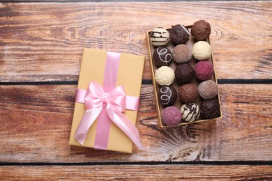 Photo of Open box with delicious chocolate candies on wooden table, top view