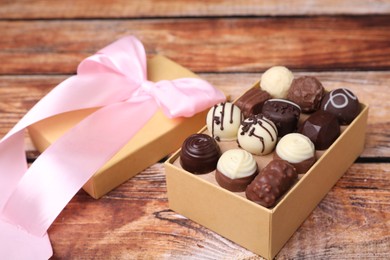 Photo of Box with tasty chocolate candies on wooden table