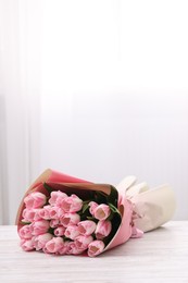 Photo of Beautiful bouquet of fresh pink tulips on white wooden table indoors. Space for text