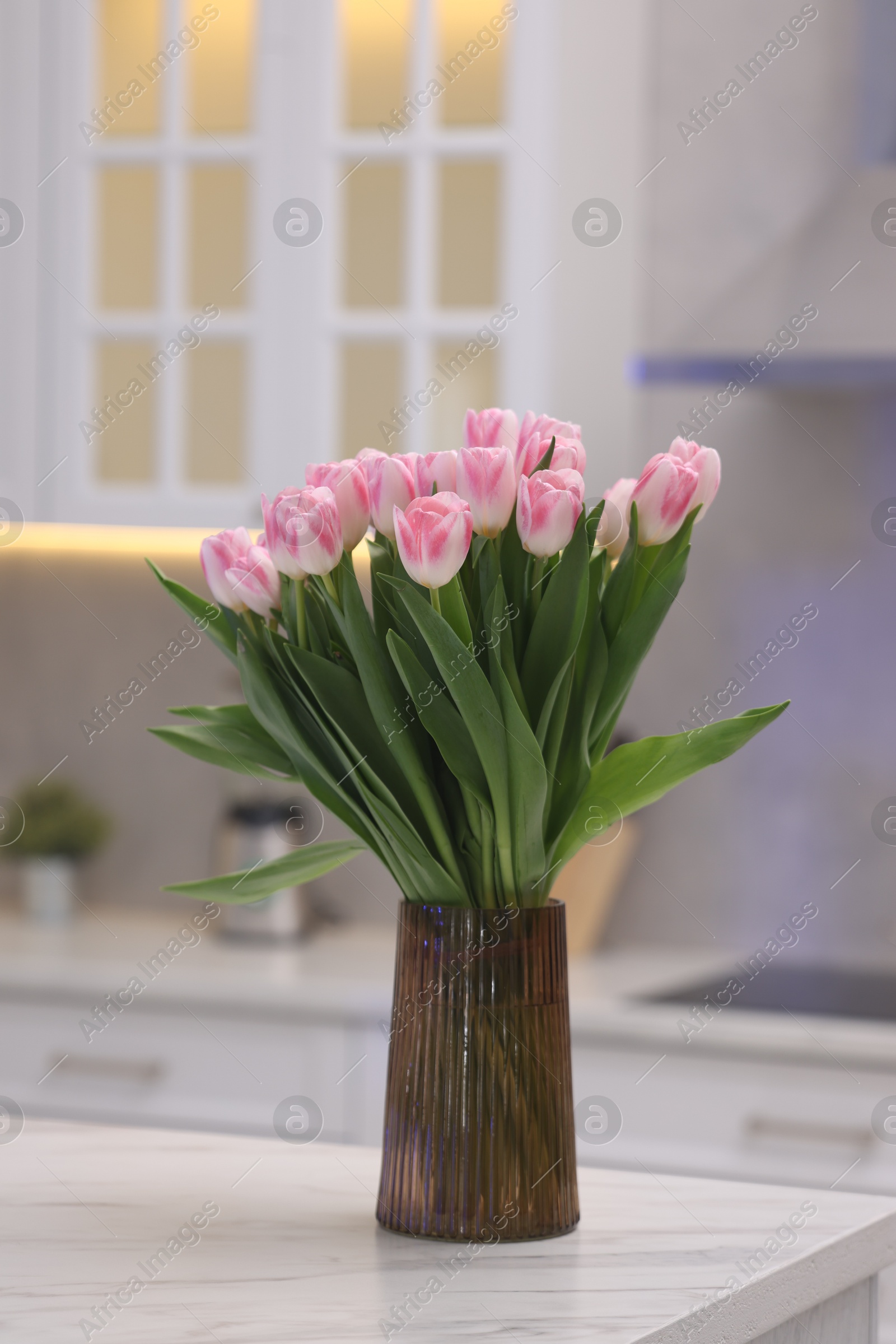 Photo of Beautiful bouquet of fresh pink tulips on table in kitchen