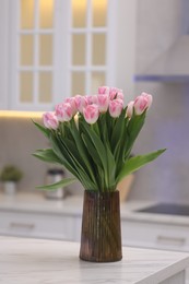 Photo of Beautiful bouquet of fresh pink tulips on table in kitchen