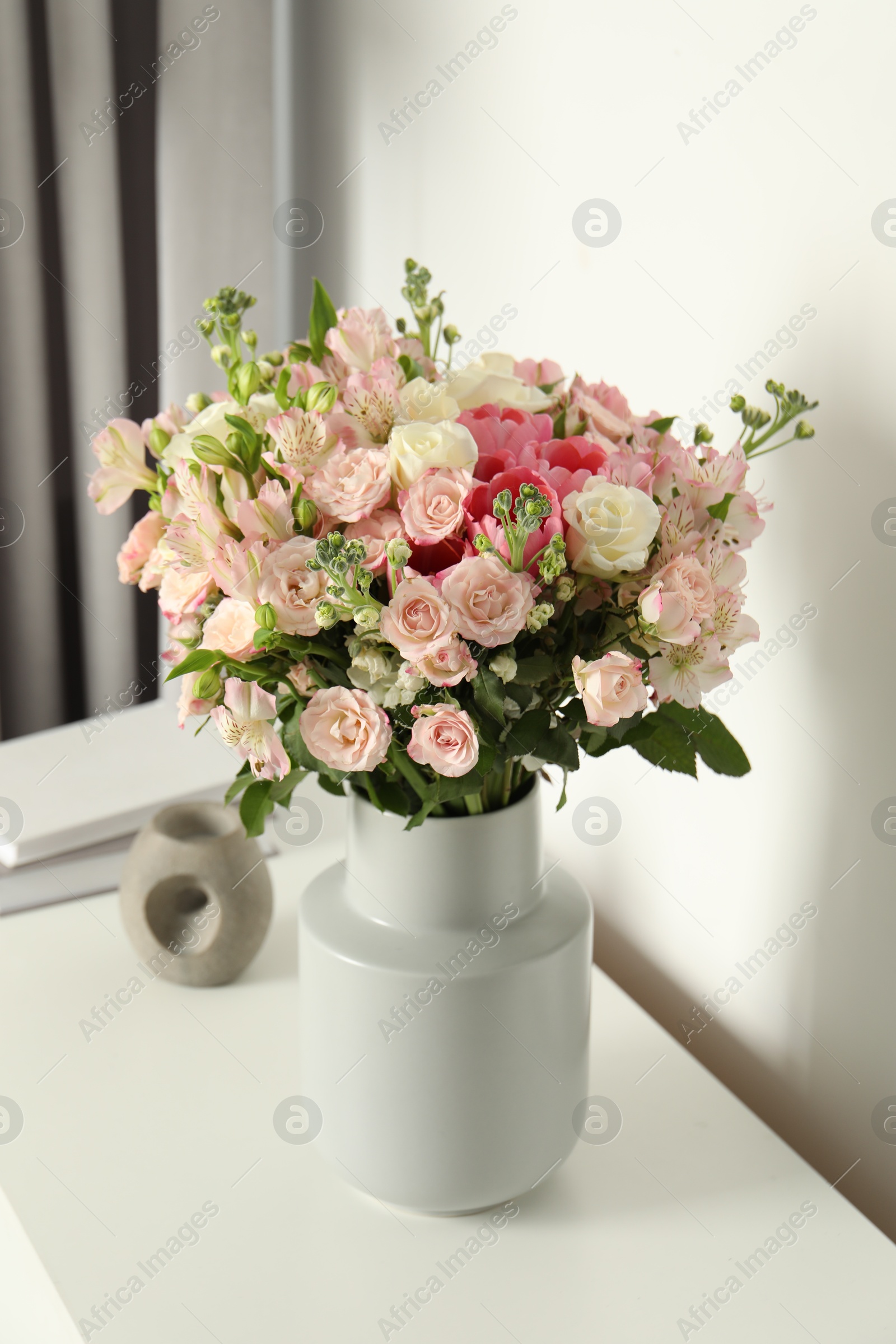 Photo of Beautiful bouquet of fresh flowers in vase on white table indoors