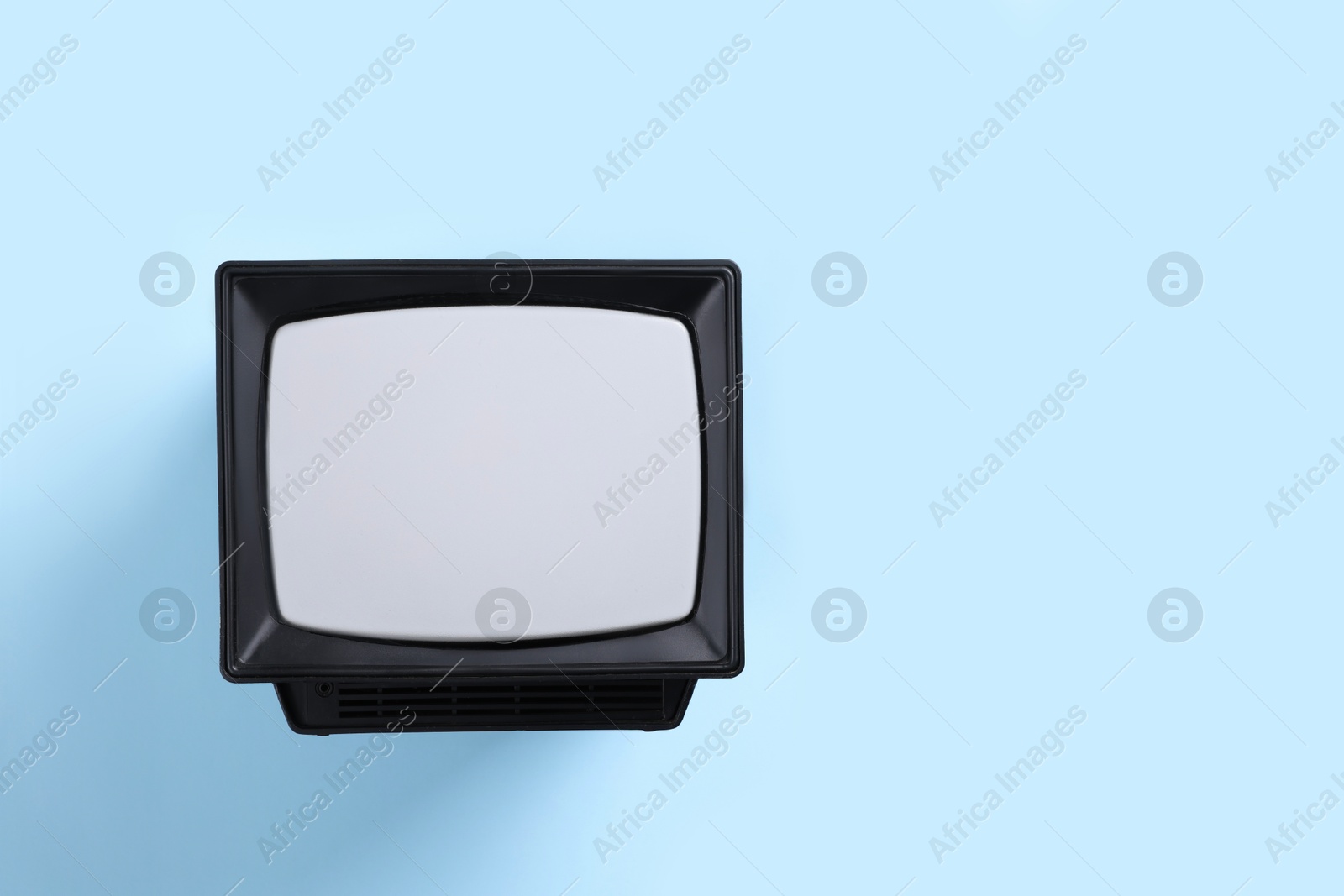 Photo of Retro tv set on light blue background, top view. Space for text