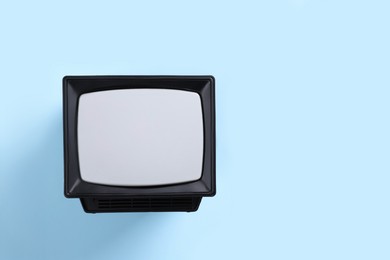 Photo of Retro tv set on light blue background, top view. Space for text