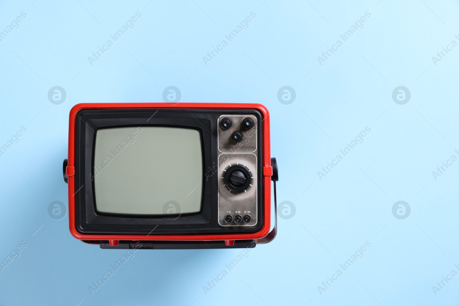 Photo of Retro tv set on light blue background, top view. Space for text