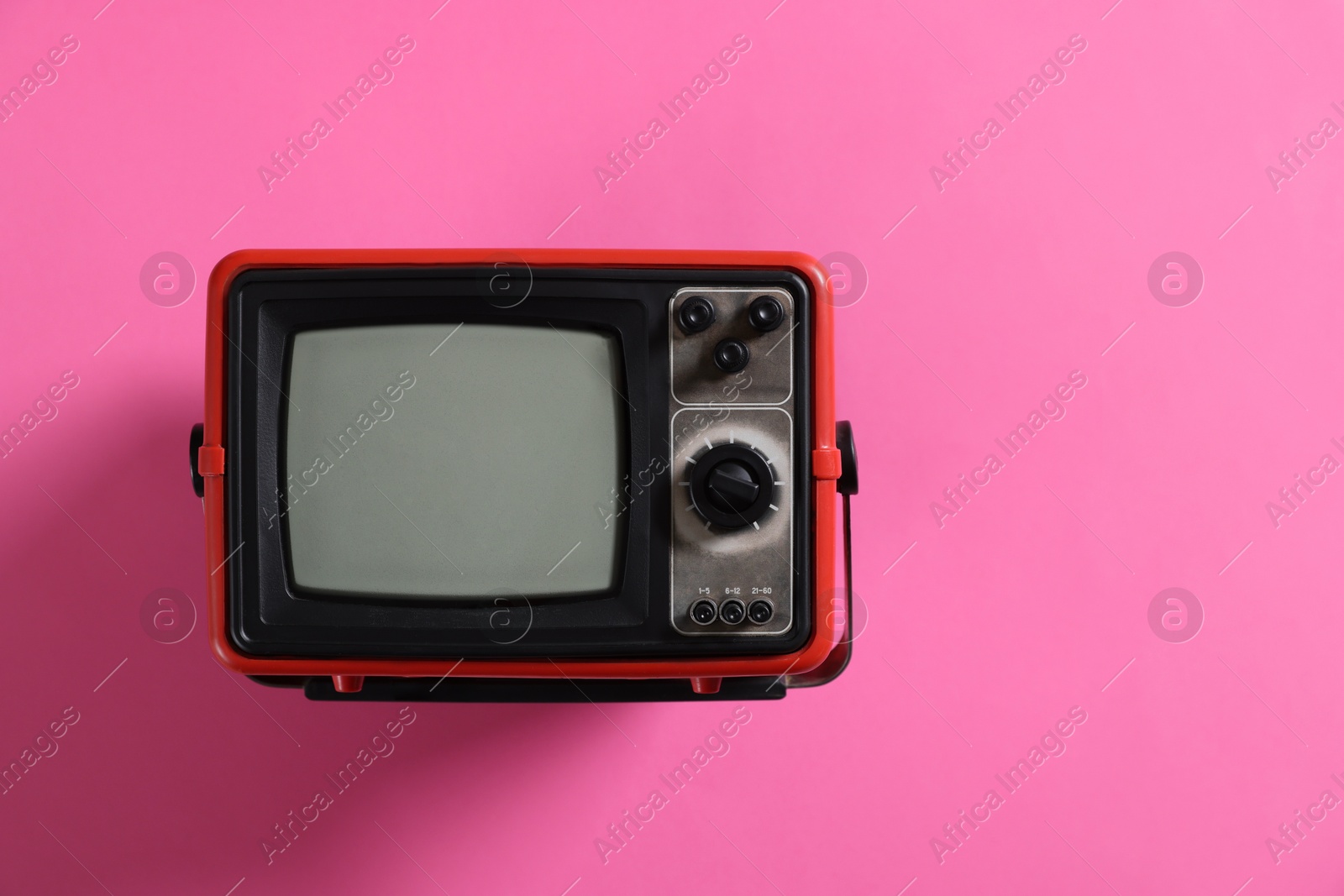 Photo of Retro tv set on pink background, top view. Space for text