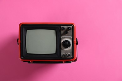 Photo of Retro tv set on pink background, top view. Space for text