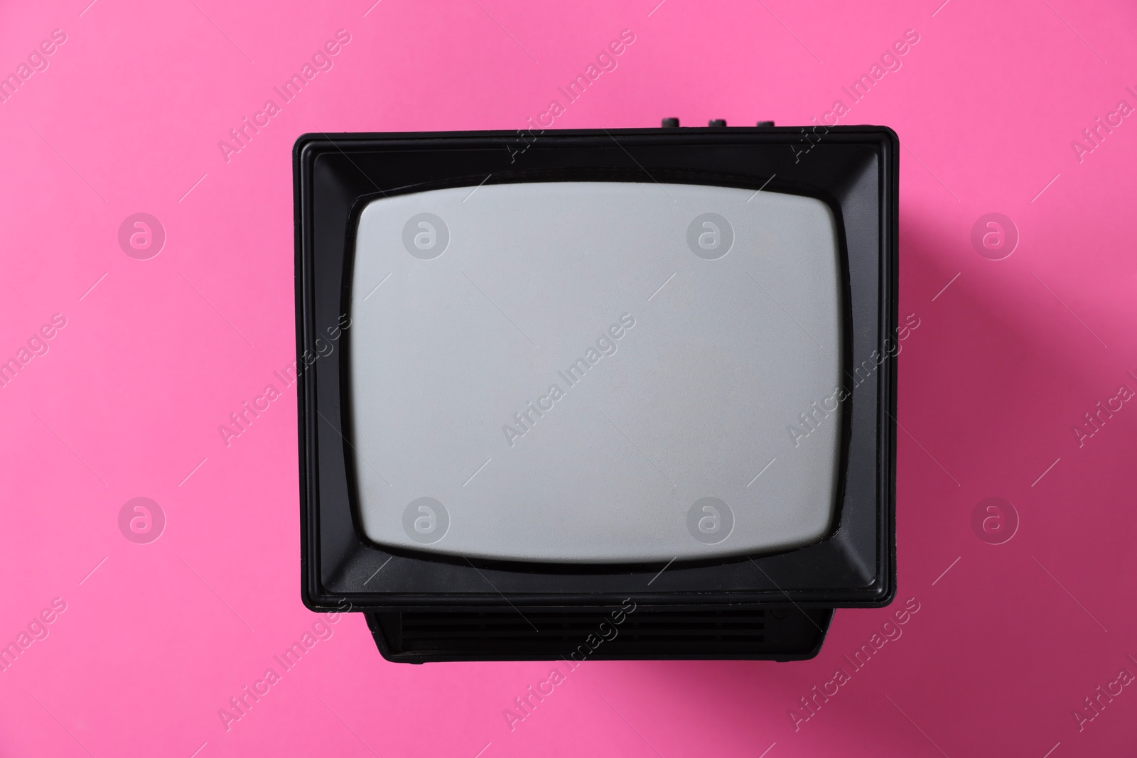 Photo of Retro tv set on pink background, top view