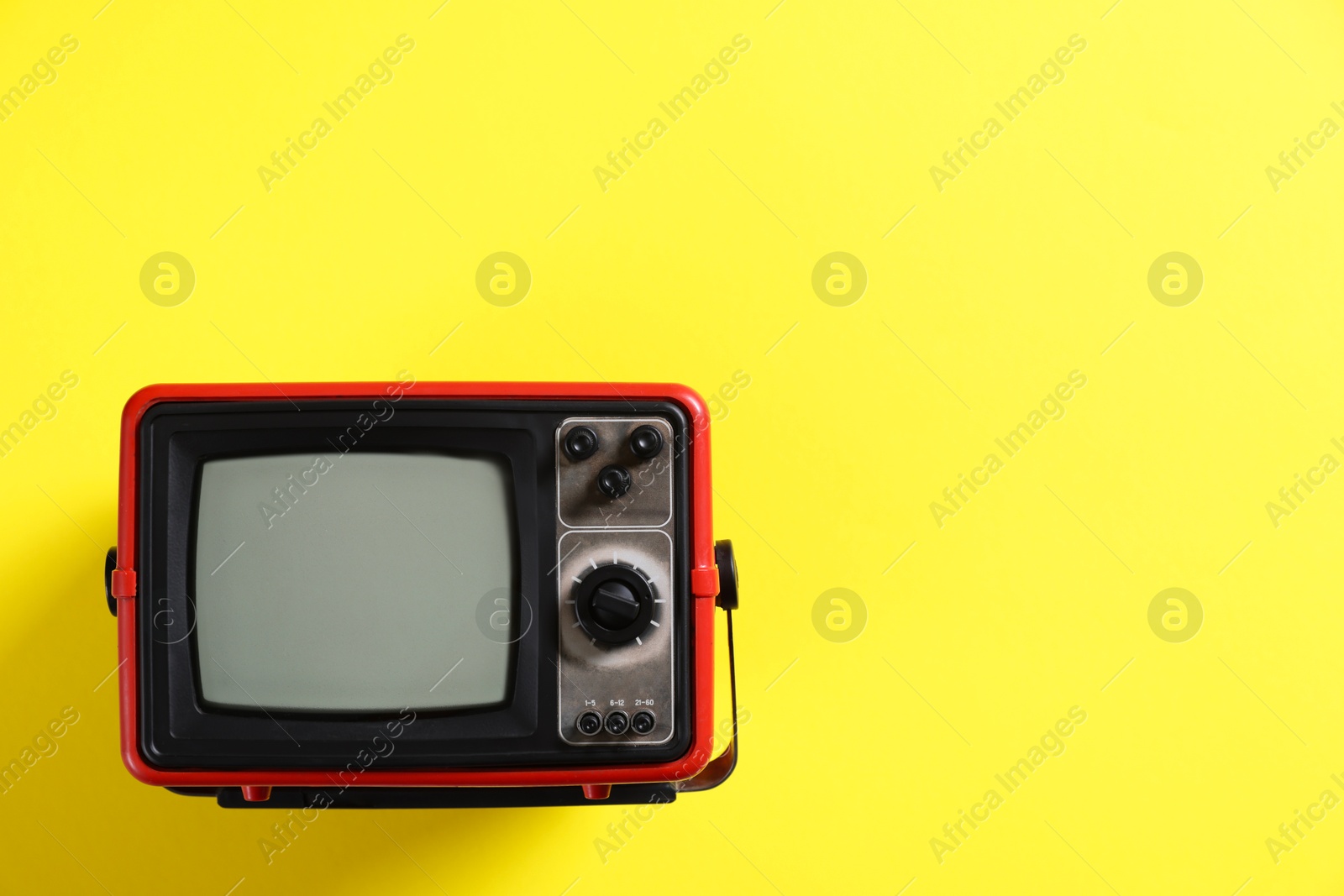 Photo of Retro tv set on yellow background, top view. Space for text