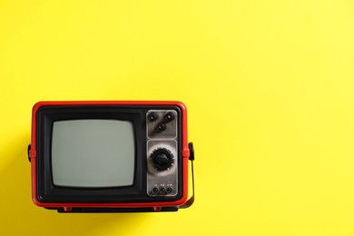 Photo of Retro tv set on yellow background, top view. Space for text