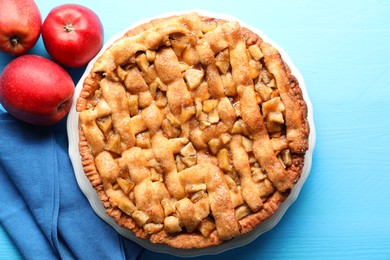 Photo of Homemade apple pie and apples on light blue wooden table, flat lay