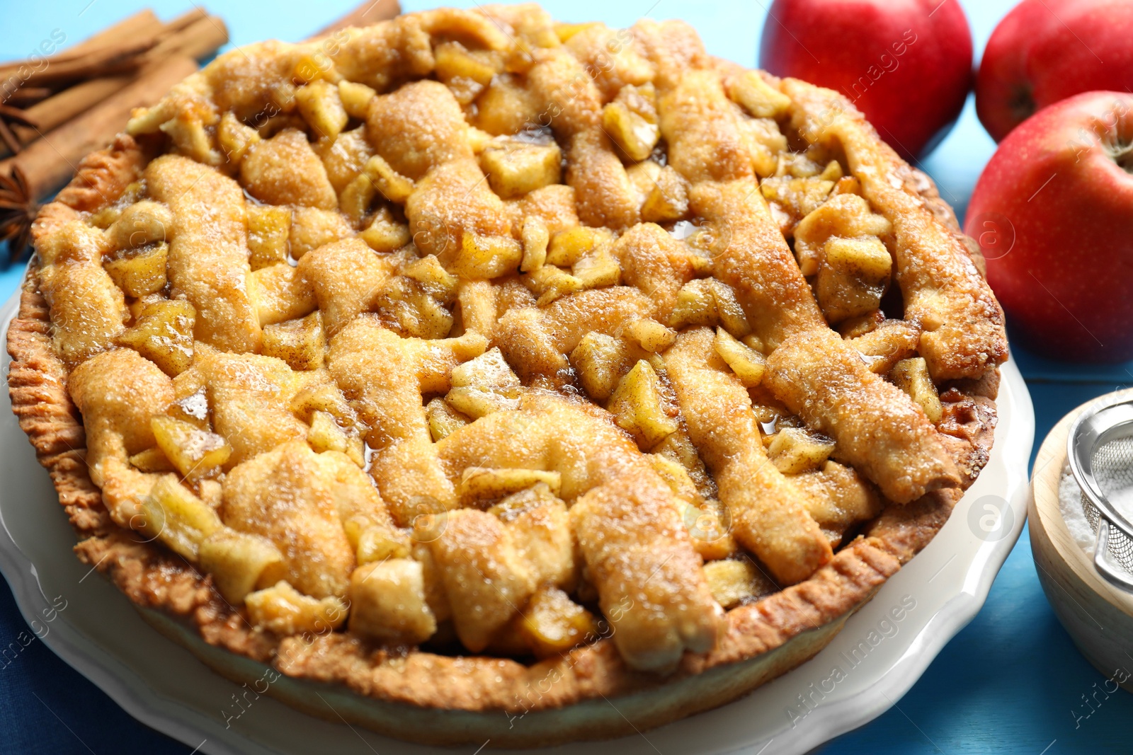 Photo of Homemade apple pie and ingredients on light blue wooden table, closeup