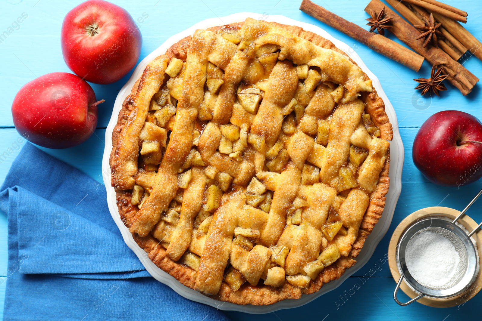 Photo of Homemade apple pie and ingredients on light blue wooden table, flat lay