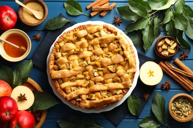 Photo of Homemade apple pie and ingredients on blue wooden table, flat lay