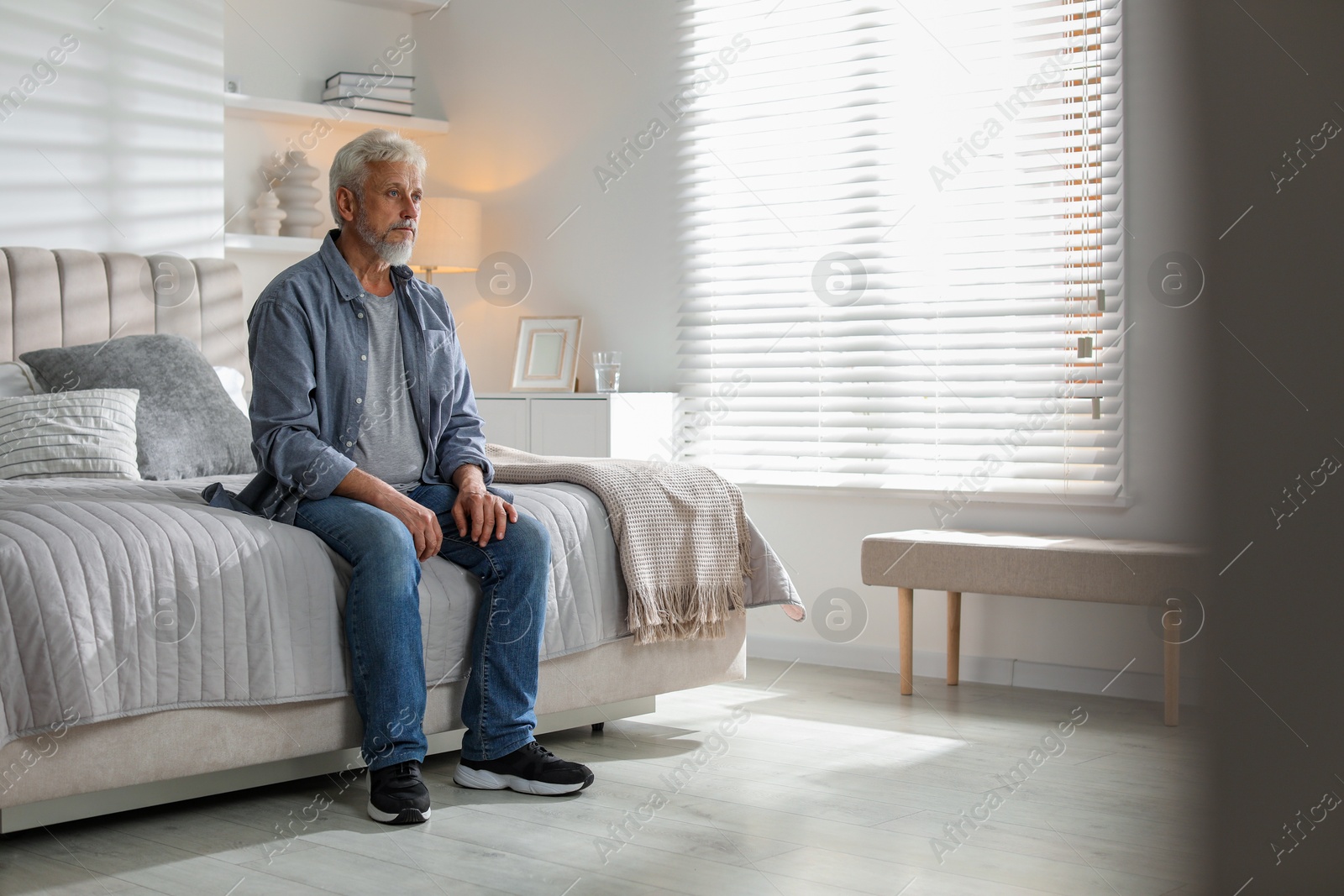 Photo of Lonely senior man sitting on bed at home