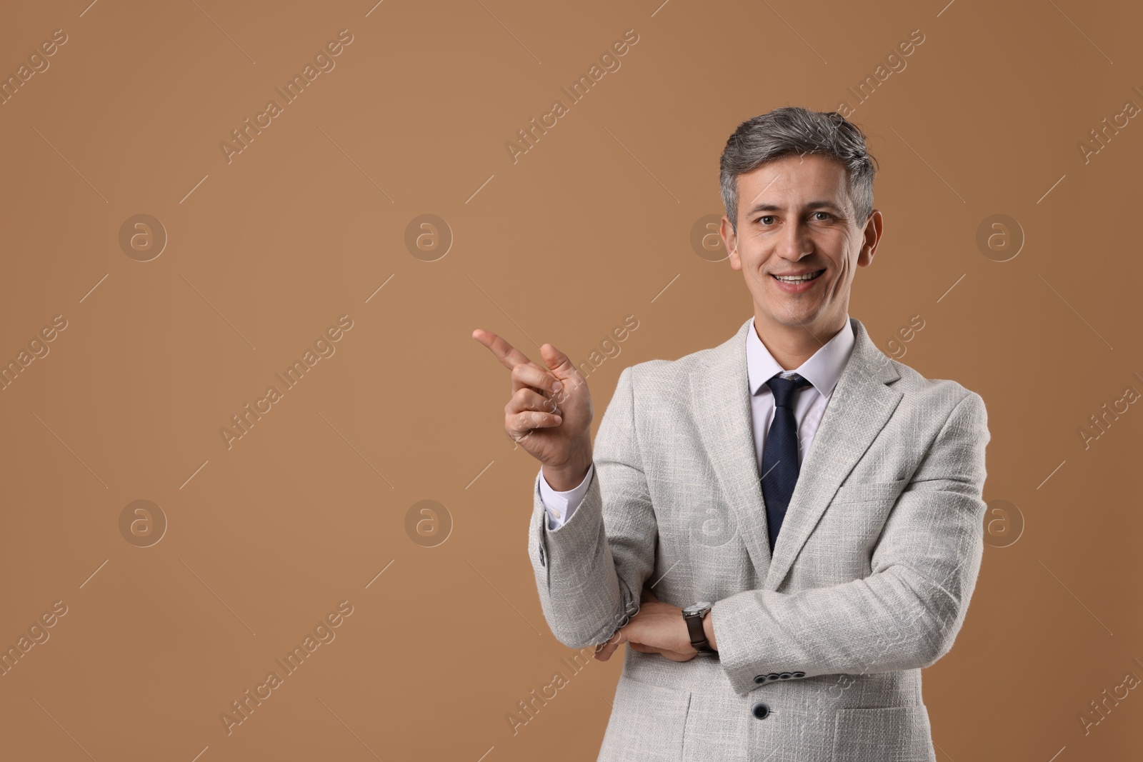 Photo of Portrait of businessman in jacket on brown background, space for text