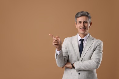 Photo of Portrait of businessman in jacket on brown background, space for text