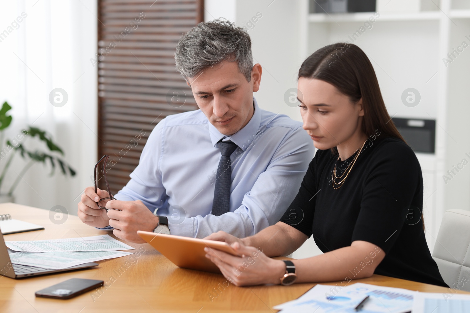 Photo of Coworkers with tablet working at table in office