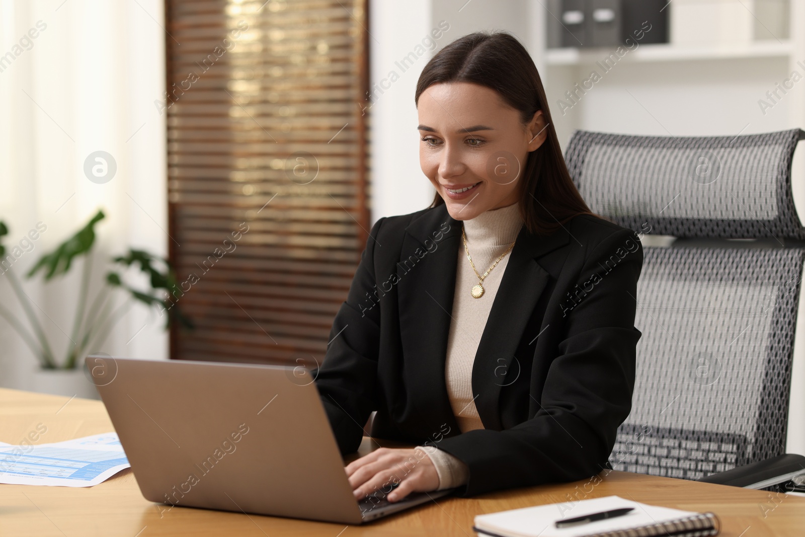 Photo of Businesswoman working with laptop at table in office