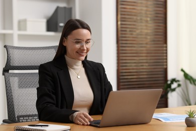 Photo of Businesswoman working with laptop at table in office