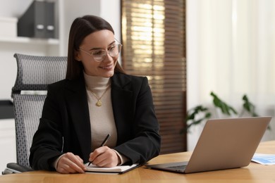 Photo of Businesswoman working at wooden table in office