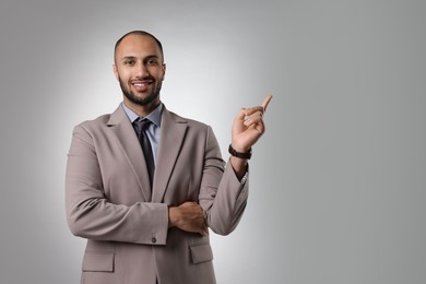 Photo of Portrait of businessman pointing at something on light gray background, space for text