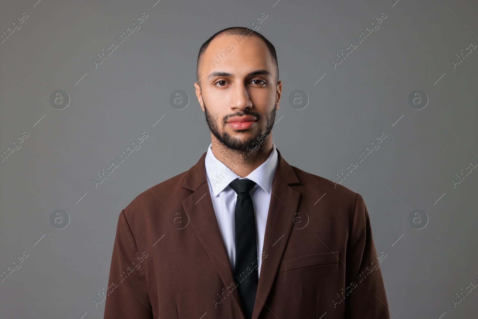 Photo of Portrait of businessman in brown jacket on gray background