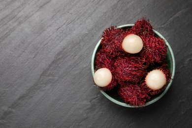 Photo of Delicious ripe rambutans in bowl on black table, top view. Space for text