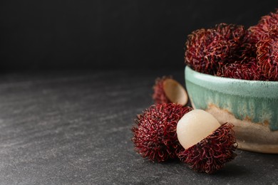 Photo of Delicious ripe rambutans in bowl on black table, closeup. Space for text