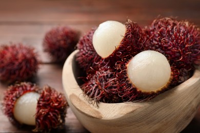 Photo of Delicious ripe rambutans in bowl on table, closeup