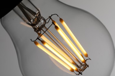 Photo of Glowing light bulb on grey background, closeup