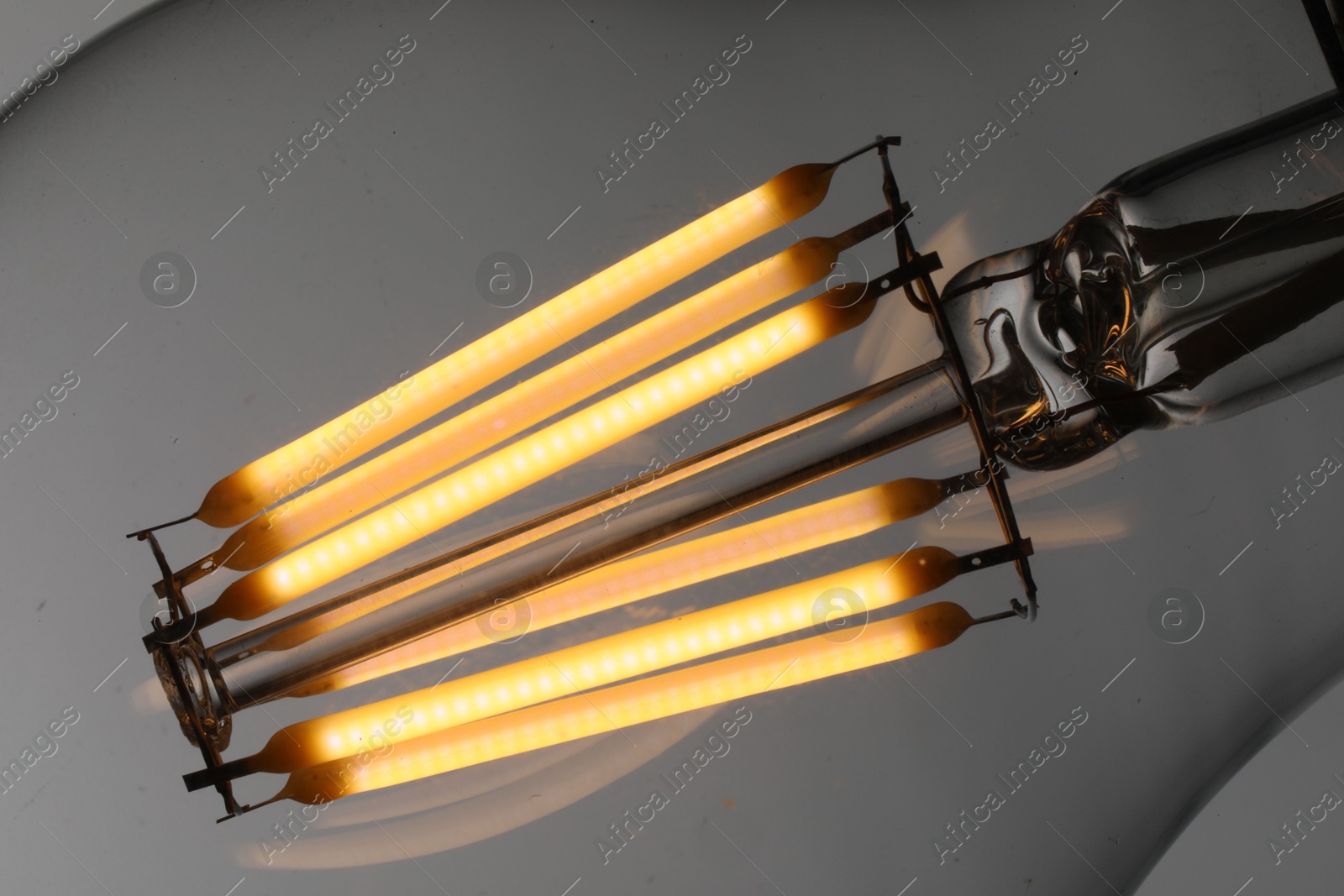 Photo of Glowing light bulb on grey background, closeup