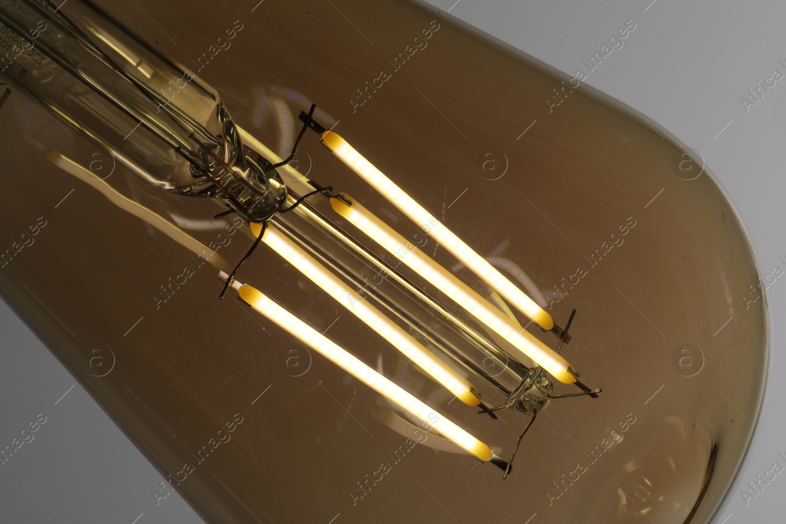 Photo of Glowing light bulb on grey background, closeup