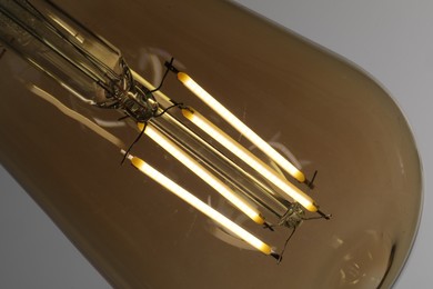 Photo of Glowing light bulb on grey background, closeup