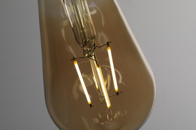 Photo of Glowing light bulb on grey background, closeup