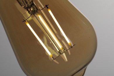 Photo of Glowing light bulb on grey background, closeup