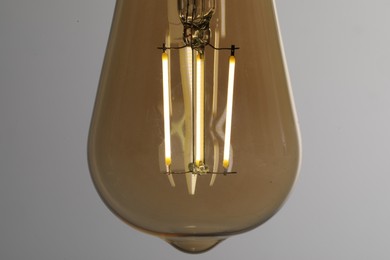 Photo of Glowing light bulb on grey background, closeup