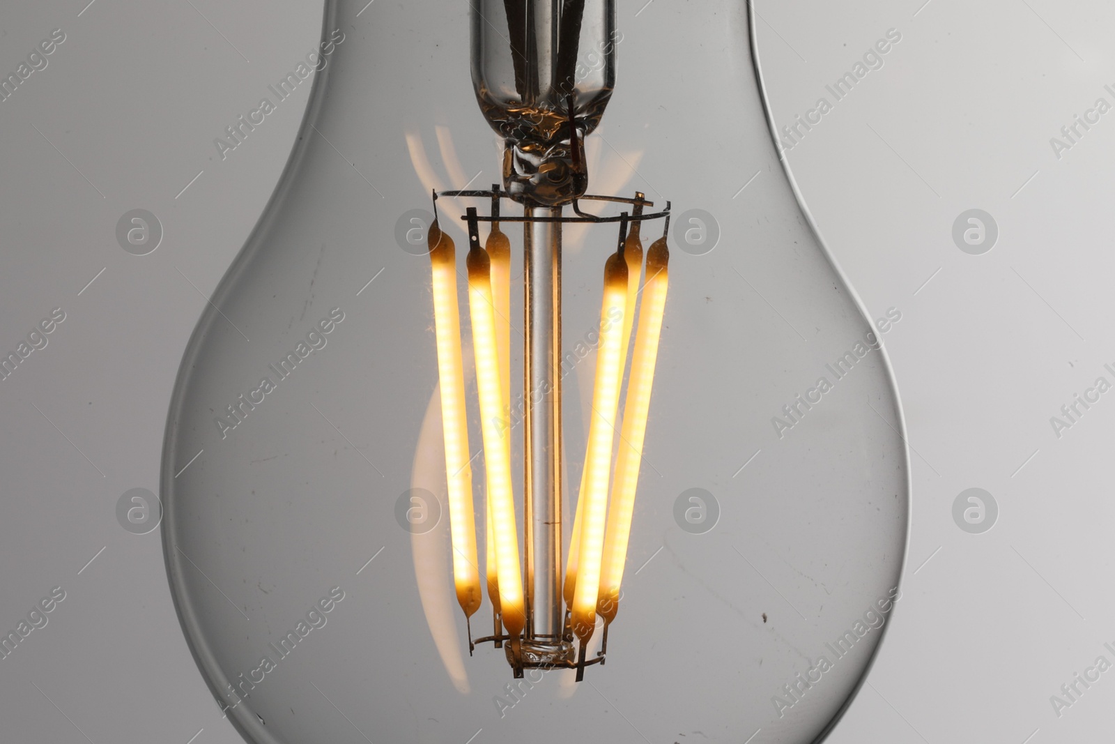 Photo of Glowing light bulb on grey background, closeup