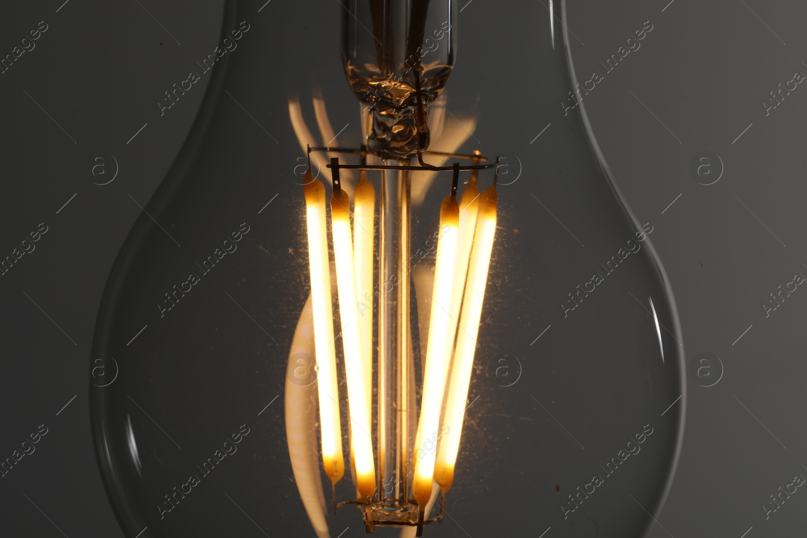 Photo of Glowing light bulb on grey background, closeup