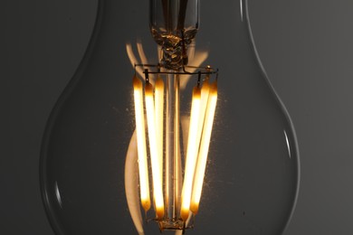 Photo of Glowing light bulb on grey background, closeup