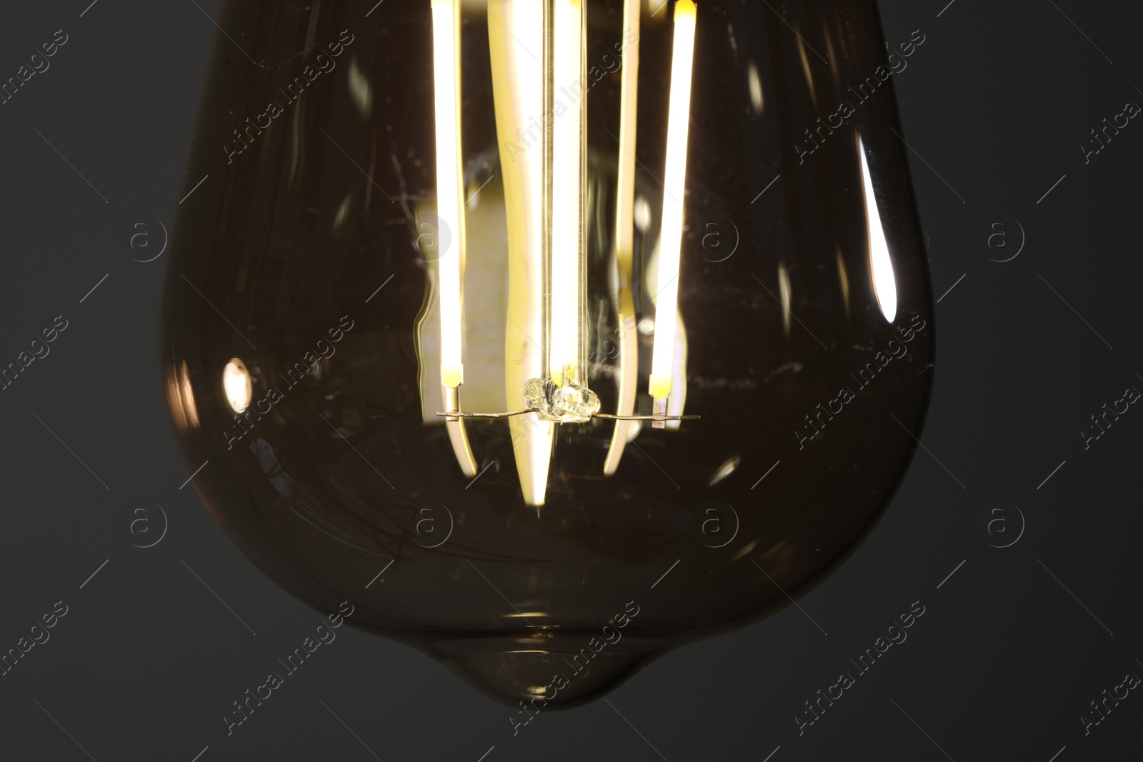 Photo of Glowing light bulb on grey background, closeup