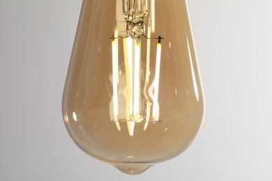 Photo of Glowing light bulb on color background, closeup