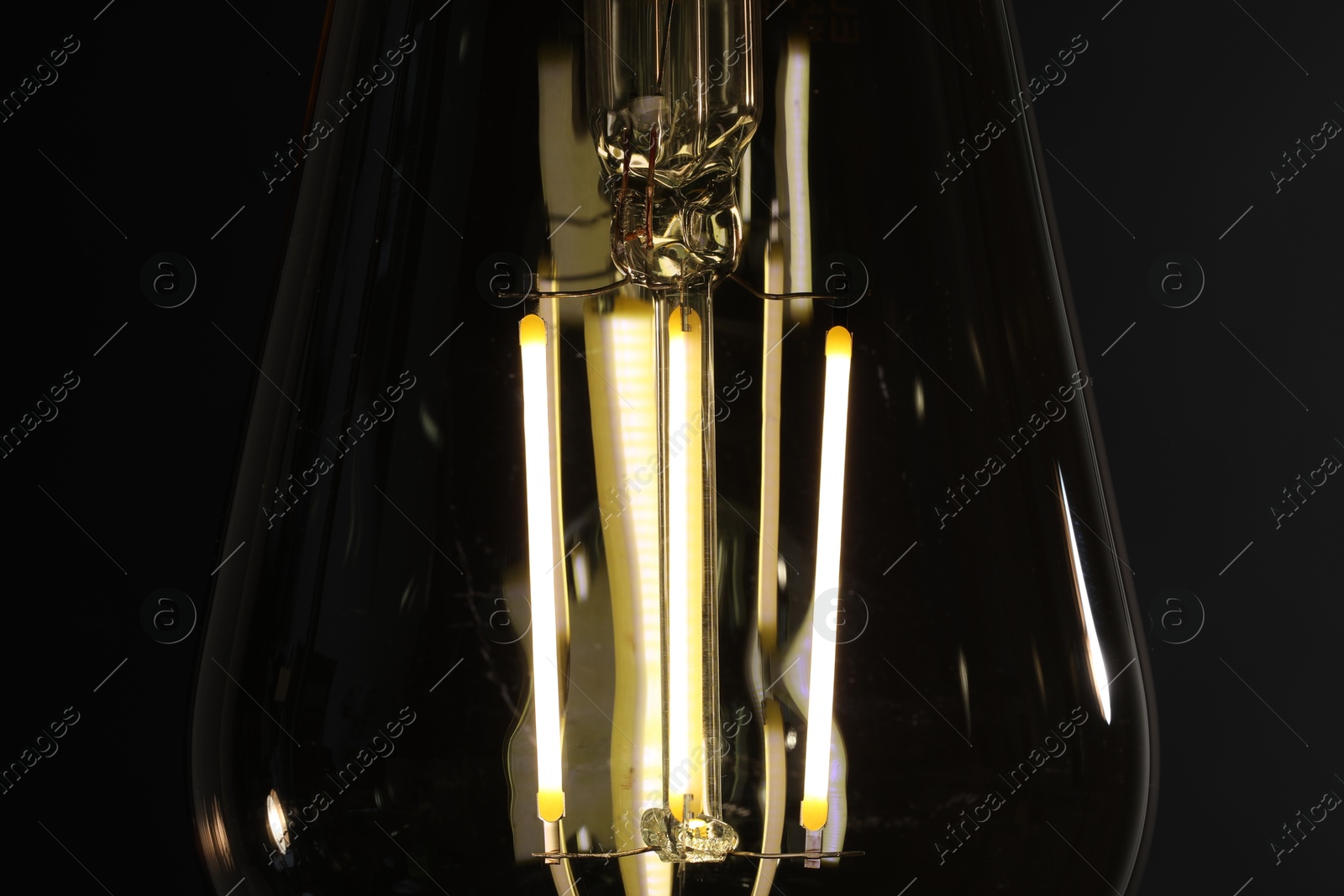 Photo of Glowing light bulb on dark background, closeup