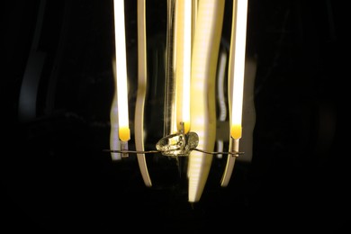 Photo of Glowing light bulb on dark background, closeup