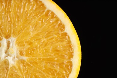 Photo of Half of fresh orange on black background, closeup. Space for text