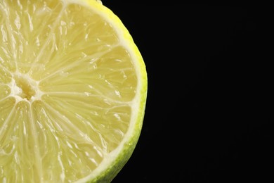 Photo of Half of fresh lime on black background, closeup. Space for text