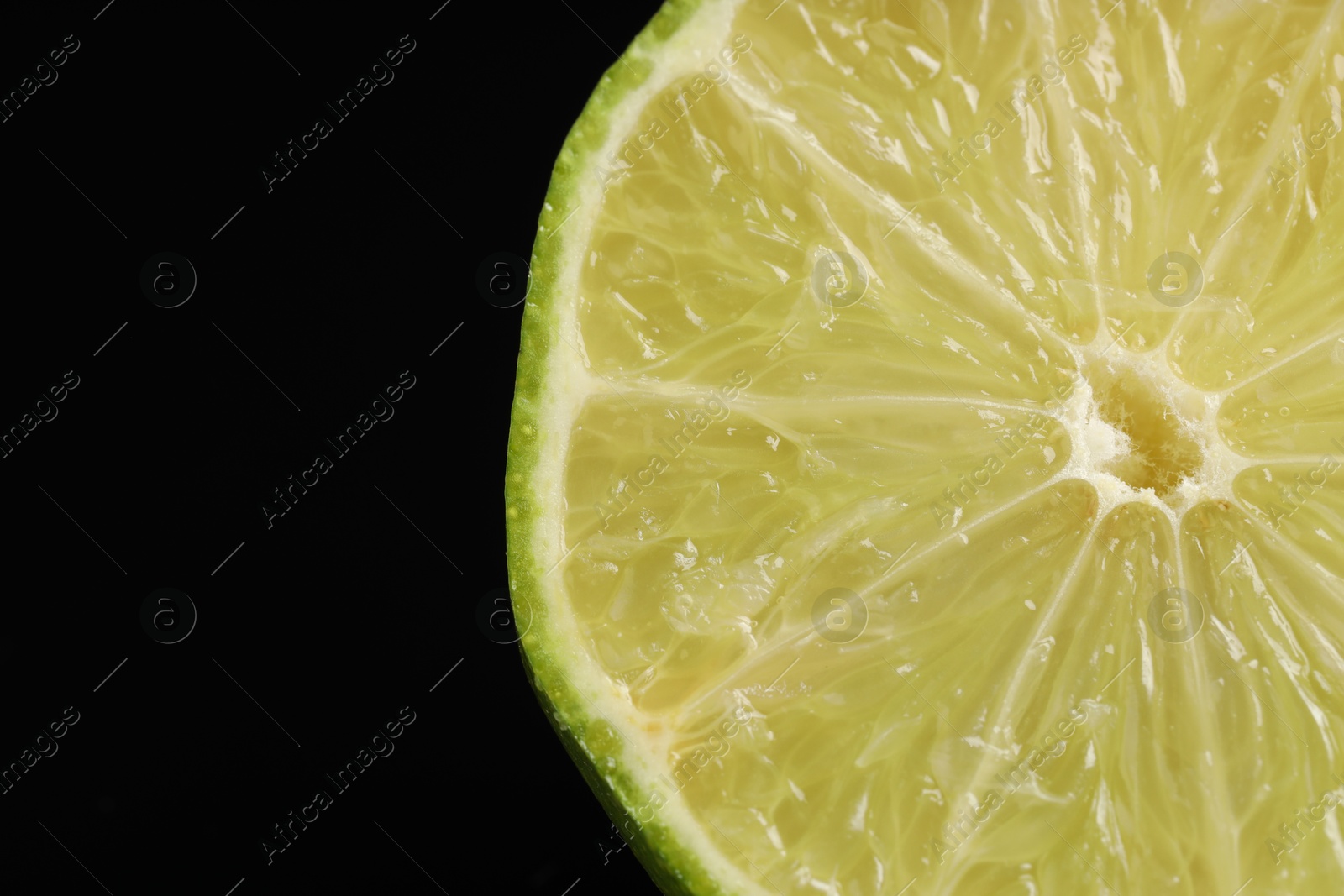 Photo of Half of fresh lime on black background, closeup. Space for text