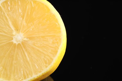 Photo of Half of fresh lemon on black background, closeup. Space for text