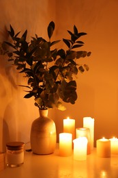 Photo of Vase with eucalyptus branches and burning candles on table in bathroom decorated for Valentine's day